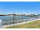Peaceful waterfront view with a railing, manicured lawn and a distant city skyline at 10215 Regal Dr # 21, Largo, FL 33774