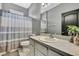 Well-lit bathroom features a vanity with white cabinets and shower with blue and white curtains at 10322 Riverburn Dr, Tampa, FL 33647