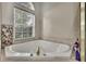 Corner soaking tub with tile surround under a window with stained glass accent at 10322 Riverburn Dr, Tampa, FL 33647