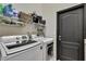 Well-organized laundry room with front loading washer and dryer plus shelving and a black door at 10322 Riverburn Dr, Tampa, FL 33647