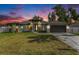 Charming single-story home with a well-manicured lawn and welcoming entrance with black double doors at sunset at 106 Ne 1St Ave, Lutz, FL 33549