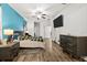 Spacious bedroom featuring hardwood floors, blue accent wall, ceiling fan, and a modern dresser at 11841 Thicket Wood Dr, Riverview, FL 33579