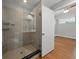 Bright bathroom featuring a glass enclosed tile shower with shelving, and wood flooring in a modern home at 1208 E Kennedy Blvd # 1125, Tampa, FL 33602