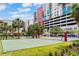 A vibrant volleyball court is surrounded by colorful buildings, palm trees, and green grass at 1208 E Kennedy Blvd # 1125, Tampa, FL 33602