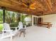 Relaxing screened patio with wood ceiling and fan, outdoor dining, chairs, and lush backyard at 12217 Snead Pl, Tampa, FL 33624