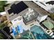 An aerial view of the home features a basketball court, pool, screened porch, and solar panels at 1326 Moss Dr, Dunedin, FL 34698
