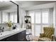 Charming bathroom with a dark vanity, decorative plants, a mirror and a comfy upholstered chair near the window at 1326 Moss Dr, Dunedin, FL 34698