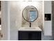 Modern bathroom vanity with round mirror, stylish tiles, and storage space at 1326 Moss Dr, Dunedin, FL 34698