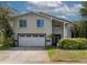Charming two-story home featuring a two-car garage, manicured landscaping, and decorative front door at 1326 Moss Dr, Dunedin, FL 34698