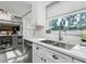 Well-lit kitchen with stainless steel sink, modern faucet, ample counter space, and custom cabinetry at 1326 Moss Dr, Dunedin, FL 34698