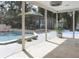 This screened-in patio looks out to the backyard, pool, cabana, and basketball court at 1326 Moss Dr, Dunedin, FL 34698