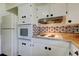 Kitchen featuring white cabinets, brick backsplash, oven, and cooktop at 1516 Lemon St, Clearwater, FL 33756