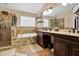 Primary bathroom featuring travertine tile, soaking tub, walk-in shower, and double vanity sinks at 1751 Split Fork Dr, Oldsmar, FL 34677