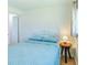 Bright bedroom features a comfortable bed with blue quilt and a bedside table with lamp at 18675 Us Highway 19 N # 140, Clearwater, FL 33764