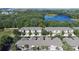 Aerial view showcasing well-maintained townhomes near a lush, wooded area and a tranquil lake at 2150 River Turia Cir, Riverview, FL 33578