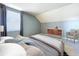 A naturally lit bedroom featuring a comfortable bed, wooden dresser and a cozy sitting chair near the window at 24314 Landing Dr, Lutz, FL 33559
