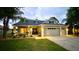 Charming home with a well-manicured lawn, beautiful landscaping, and illuminated exterior lights at 24314 Landing Dr, Lutz, FL 33559