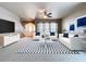 The staged living room has a white sofa set, geometrically patterned carpet, a ceiling fan, and a staircase in the background at 24314 Landing Dr, Lutz, FL 33559