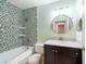 Well-lit bathroom featuring a tub with tiled walls, a dark vanity with a white marble countertop, and a round mirror at 2604 Shilo Ct, Valrico, FL 33596