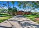 Long driveway leading up to the exterior of the home with lush greenery, palm trees, and stone accents at 29909 Baywood Ln, Wesley Chapel, FL 33543