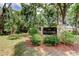 Community sign for The Meadows featuring stone pillars, black signage, manicured landscaping, and lush trees at 3310 Tanglewood Trl, Palm Harbor, FL 34685
