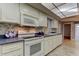 Modern kitchen featuring range, microwave, tile floors, and custom cabinets at 3310 Tanglewood Trl, Palm Harbor, FL 34685