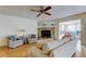 Cozy living room features a stone fireplace, ceiling fan, and hardwood flooring, creating a warm and inviting space at 3310 Tanglewood Trl, Palm Harbor, FL 34685