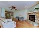 Bright living space featuring a stone fireplace, ceiling fan, hardwood flooring, and comfortable furnishings at 3310 Tanglewood Trl, Palm Harbor, FL 34685