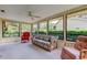 Light-filled sunroom with plush seating, offering relaxing views of the surrounding green landscape at 3310 Tanglewood Trl, Palm Harbor, FL 34685