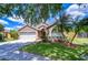 Charming home featuring a well-manicured lawn, mature trees, and an attached two-car garage at 4503 Lace Cascade Ct, Lutz, FL 33558