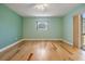 Empty bedroom showcases hardwood floors, light green walls, a window, and a sliding glass door at 4801 Airport Rd # 214, Zephyrhills, FL 33542