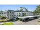 White condo building features balconies, a stone stairwell, and a covered parking area at 4801 Airport Rd # 214, Zephyrhills, FL 33542