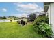 The backyard is spacious and green with a grill and a view of the lake and neighboring houses at 4810 Diamonds Palm Loop, Wesley Chapel, FL 33543