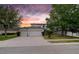 Two-story home with a three-car garage and landscaped yard at sunset at 4810 Diamonds Palm Loop, Wesley Chapel, FL 33543