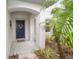 Inviting front porch with a navy blue door, decorative wreath, and lush tropical landscaping at 4810 Diamonds Palm Loop, Wesley Chapel, FL 33543
