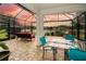 Screened-in patio with an outdoor dining set and seating overlooking a peaceful lake at sunset at 4810 Diamonds Palm Loop, Wesley Chapel, FL 33543