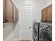 Laundry room with modern washer and dryer set, white door, and upper wood cabinets for storage at 525 Manns Harbor Dr, Apollo Beach, FL 33572