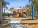 A covered playground with slides and climbing features surrounded by palm trees and lush landscaping at 525 Manns Harbor Dr, Apollo Beach, FL 33572