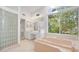 Bathroom featuring a glass block wall, a tub, vanity, and a large window with a peaceful view at 6014 Luana S Ln, Gulfport, FL 33707