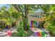 Unique home exterior showcasing a colorful painted driveway and garage doors, surrounded by lush greenery and palm trees at 6014 Luana S Ln, Gulfport, FL 33707