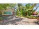 Garage featuring colorful artwork on doors, complemented by tropical landscaping and a vibrant driveway at 6014 Luana S Ln, Gulfport, FL 33707