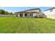 Lush green backyard featuring a covered patio, manicured lawn and privacy fence at 6700 Devlin Ln, Wesley Chapel, FL 33545