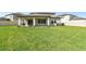 Large backyard featuring lush green lawn and covered patio with modern hanging chairs at 6700 Devlin Ln, Wesley Chapel, FL 33545