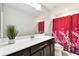 Bright bathroom featuring a quartz countertop, dark cabinetry, large mirror and a shower with a red shower curtain at 6700 Devlin Ln, Wesley Chapel, FL 33545