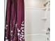 A close-up of a bath tub with white acrylic surround and an artistic red and white shower curtain at 6700 Devlin Ln, Wesley Chapel, FL 33545