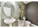 Chic powder room features an oval mirror, pedestal sink, and decorative wall art at 6700 Devlin Ln, Wesley Chapel, FL 33545