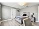 Well-lit bedroom with light grey walls, wood-look floors, and a modern bed with decorative pillows at 6700 Devlin Ln, Wesley Chapel, FL 33545