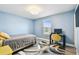 Blue bedroom featuring a window, a bed with a grey comforter, a desk and a colorful rug at 6700 Devlin Ln, Wesley Chapel, FL 33545