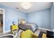 Cozy blue bedroom with light wood-look floors and a bed with a grey comforter and yellow accents at 6700 Devlin Ln, Wesley Chapel, FL 33545