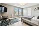 Neutral-toned bedroom featuring a desk, rug, bed with grey blanket, and natural light from two windows at 6700 Devlin Ln, Wesley Chapel, FL 33545